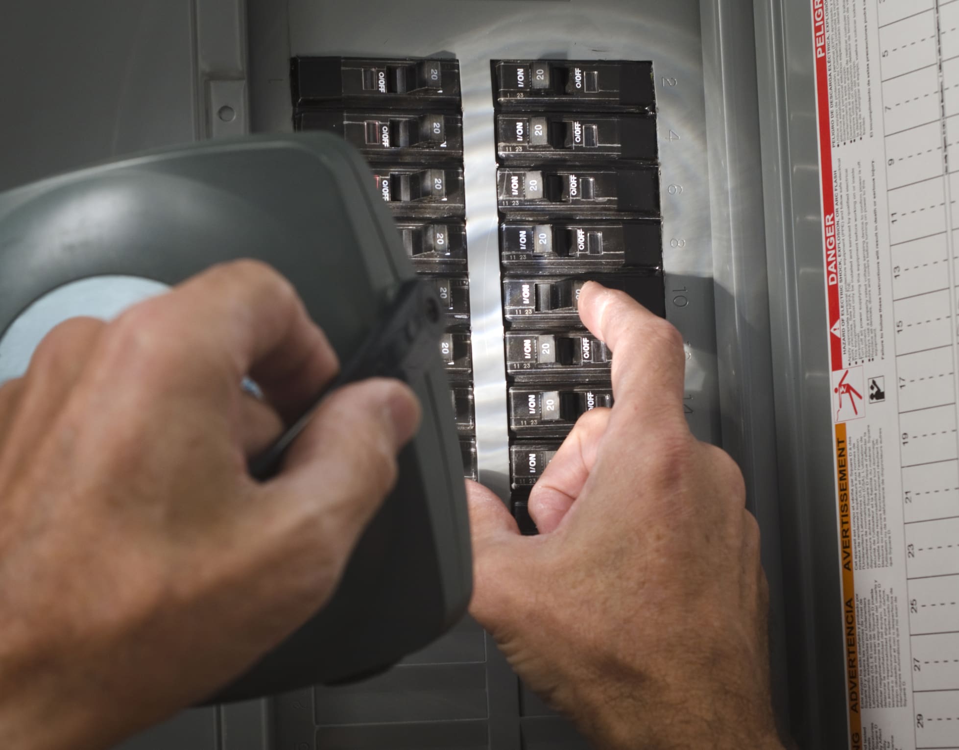 Man with Flashlight Resetting Circuit Breaker