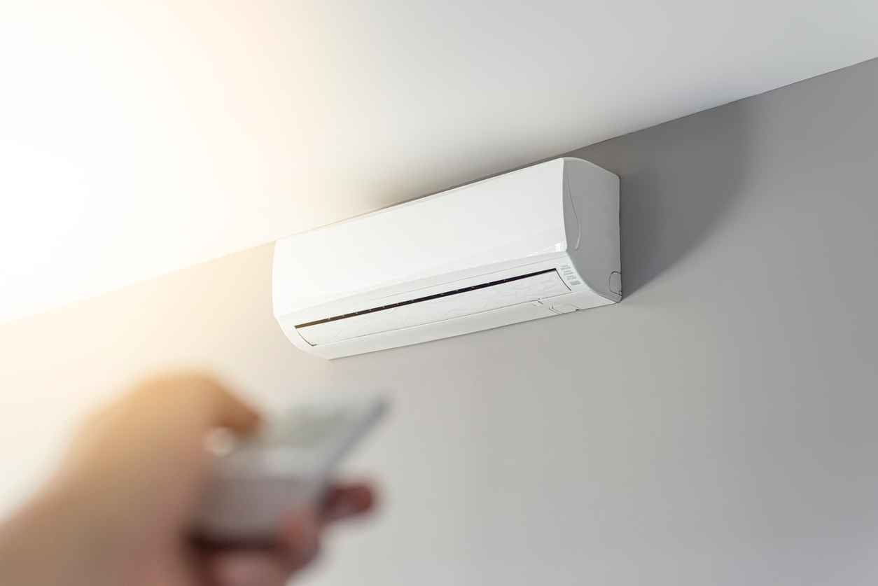A man shutting down the air conditioner with remote control.