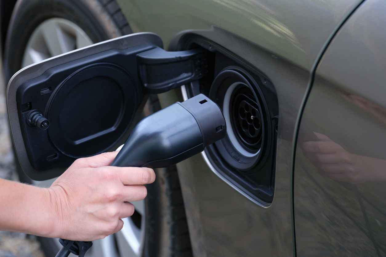 Man inserting electric cable into car charger closeup.
