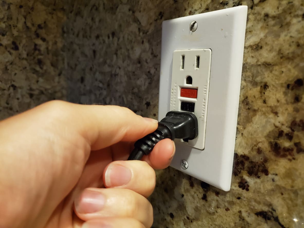 Hand Plugging in Cord to GFCI Outlet