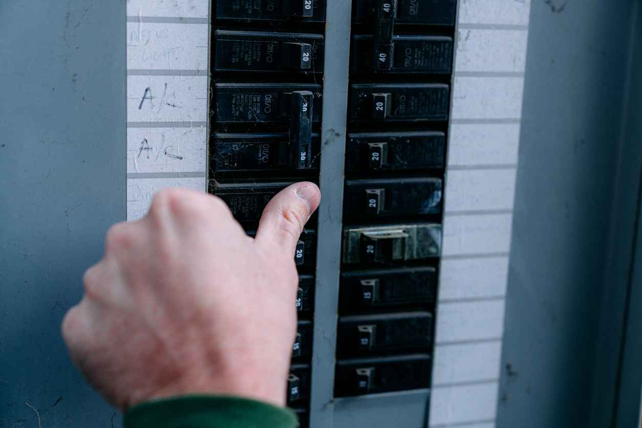 Close-Up Shot of a Man's Hand Checking or Turning on/off a Circuit Breaker on a home outdoor panel in the USA