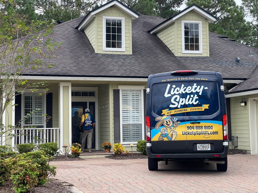 A Lickety-Split Plumbing, Electric, and A/C technician arrives at a Jacksonville home with a branded service van parked in the driveway.