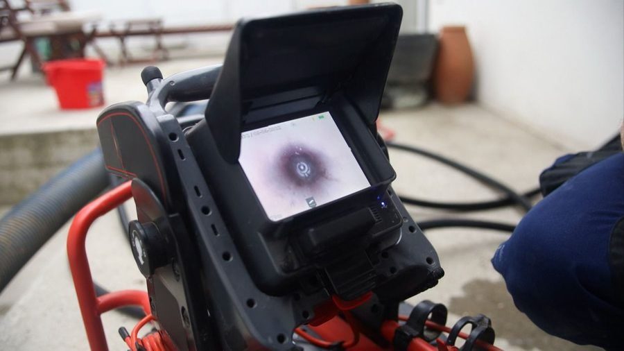 Handheld inspection monitor on a red cart displaying a circular target pattern on the screen